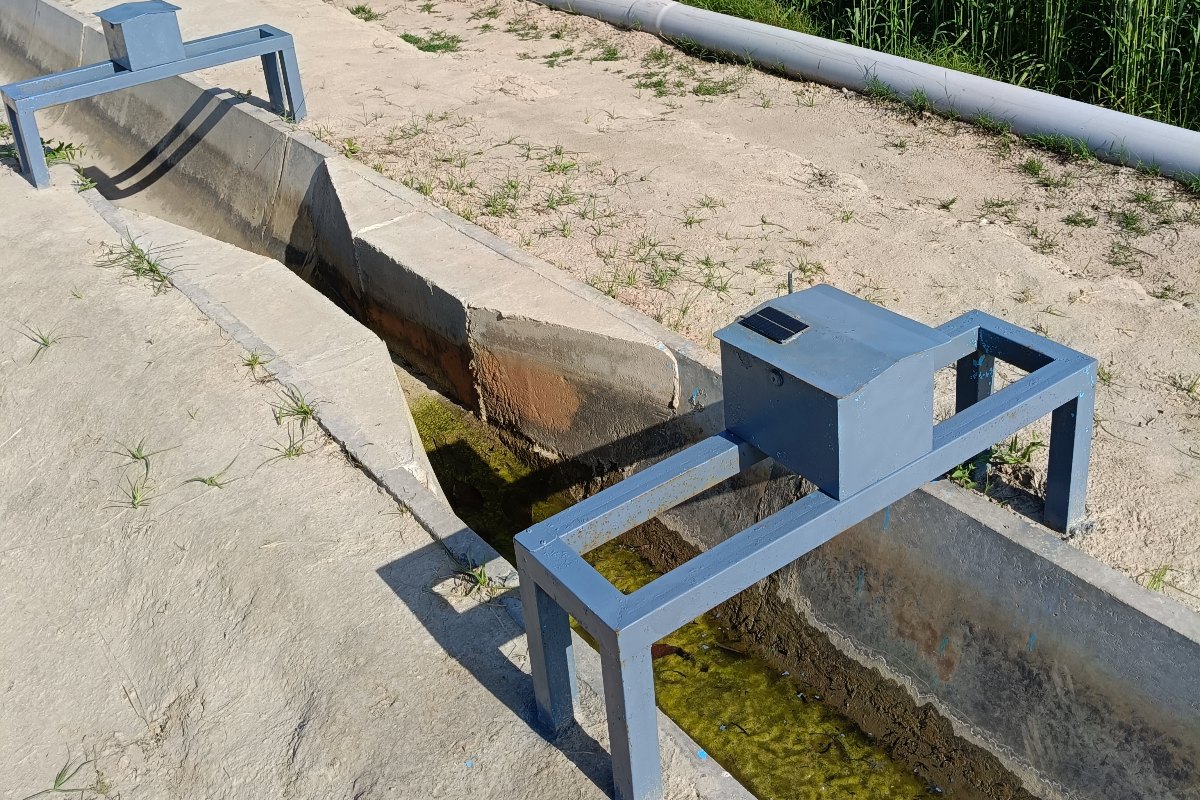 Company Overview Solar powered water level gauge mounted on a steel frame over a lined concrete watercourse beside a wheat field